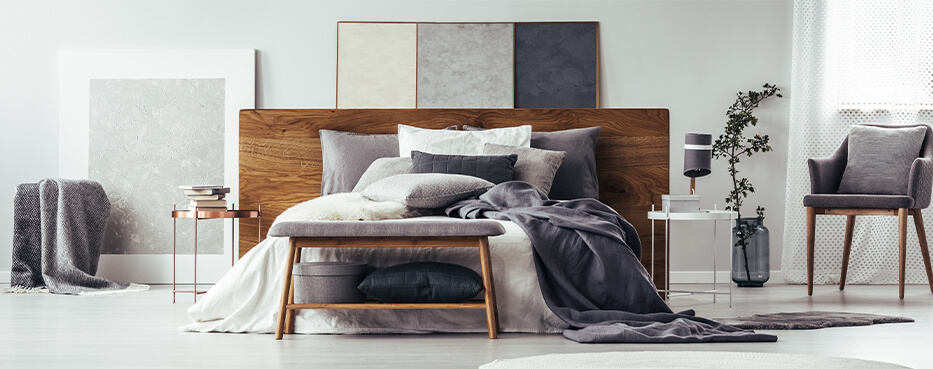 Bedroom with different shades of grey interior and bed with wooden headboard and comfy greyish bedding